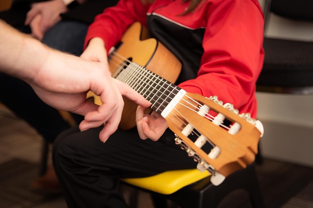 Yakın çekimde gitar çalmayı öğrenen çocuk görseli.